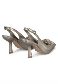 Talons slingback argent métallique avec un bout pointu, ornés de décorations florales et d'un talon de hauteur moyenne pour une stabilité accrue.