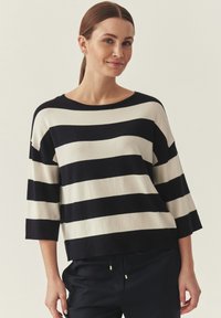 Pull rayé marine et ivoire, large encolure bateau, manches trois-quarts, texture douce, coupe décontractée, agrémenté d'accents métalliques dorés.