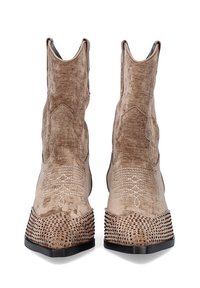Botas occidentales beige con una superficie suave y texturizada, costuras decorativas y acentos perforados en la base. Diseño de punta cuadrada.