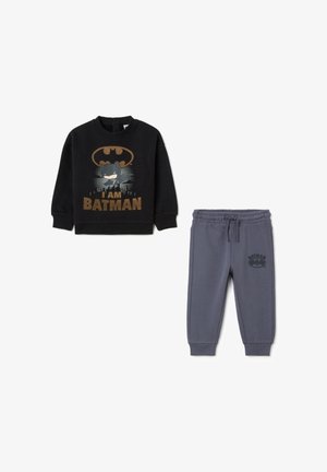 Sudadera negra con gráfico "SOY BATMAN" y pantalones de chándal grises con el logo de Batman. Presenta una cinturilla elástica y tobillos ajustados. Material suave.