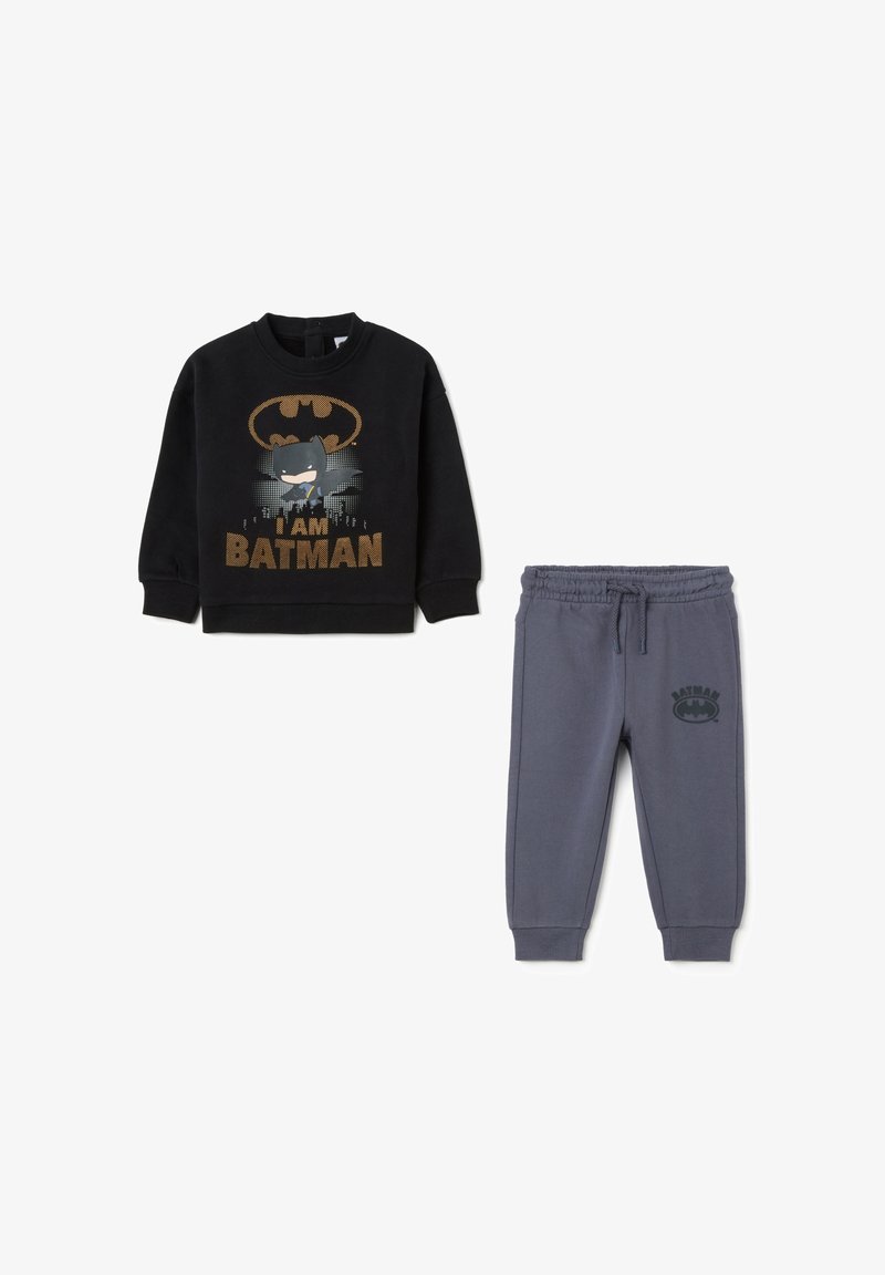 Sudadera negra con gráfico "SOY BATMAN" y pantalones de chándal grises con el logo de Batman. Presenta una cinturilla elástica y tobillos ajustados. Material suave.