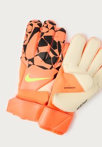 Golmanske rukavice u živopisnoj narančastoj boji s crnim geometrijskim uzorcima. Imaju teksturiranu dlan, prilagodljivu narukvicu i Nike oznaku.