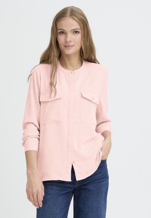 Camicia button-up rosa chiaro con maniche lunghe, due tasche sul petto e colletto arrotondato, abbinata a jeans di denim. Tessuto dalla superficie liscia.