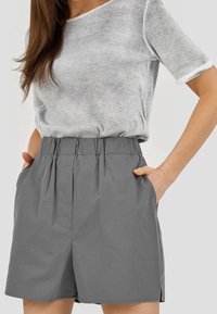 Szare, wysokie szorty z elastycznym pasem, kieszeniami bocznymi i gładką teksturą. Ułożone z jasnoszarym swetrem.