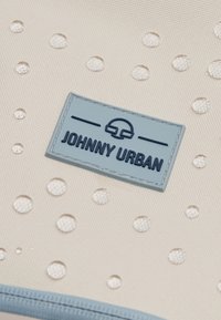 Fehér vízálló táska kiemelkedő textúrával és vízcseppekkel. Kék gumilogo, rajta sötétkék szöveggel: "JOHNNY URBAN".