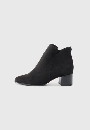 Bottines en suède noir avec un bout pointu, un petit talon carré et un design découpé au niveau de la cheville pour un look moderne.
