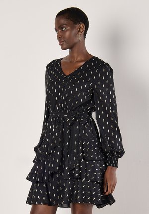 Schwarzes Kleid mit V-Ausschnitt, langen Ärmeln und gerafften Lagen. Mit goldenen Blätternmuster und einem gebundenen Taillengurt für die Silhouette. Aus glattem Stoff.