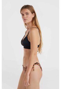 Čierny bikiny vrch s tenkými popruhmi v kombinácii s mnohobarevnými prúžkovanými bikiny spodkami s viazaním na bokoch. Hladký povrch látky.