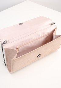 Clutch in suede rosa pallido con chiusura a scatto, dotata di tracolla a catena e tasca interna con zip per un'organizzazione sicura. Texture liscia su tutta la superficie.