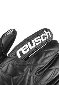 Schwarze Torwart-Handschuhe mit strukturierten Oberflächen und geometrischen Mustern. Mit auffälligem weißen "reusch"-Branding am Handgelenk.