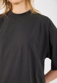 T-shirt preta de manga curta, feita de algodão macio, com um decote redondo e um corte descontraído, apresentando uma textura suave e detalhes de costura minimalistas.