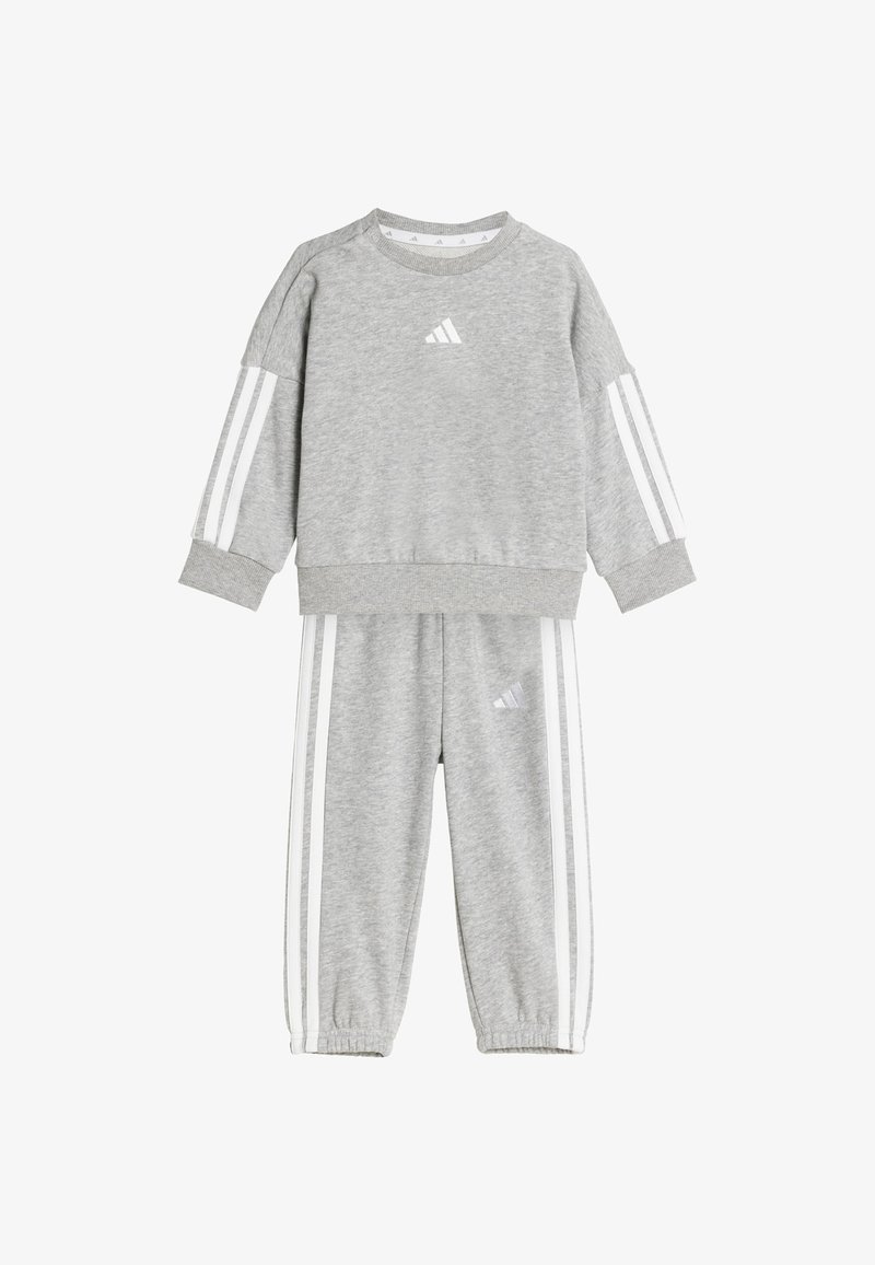 Grijze sweatshirt en broek set, gemaakt van zachte stof. Kenmerkend zijn de witte strepen op de mouwen en broek, met een klein logo op de borst en dij.