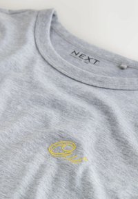 Siva bombažna majica z okroglim izrezom in rumenim vezenim napisom "Oui" na sprednji strani. Mehka tekstura s sproščenim krojem.