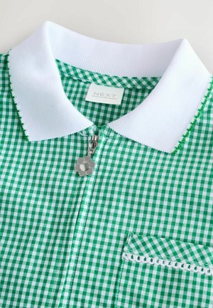 Grünes und weißes Gingham-Hemd mit Kragen und Reißverschluss, ausgestattet mit einem dekorativen, blumenförmigen Reißverschlussanhänger und einer kleinen Tasche mit Spitzenbesatz.