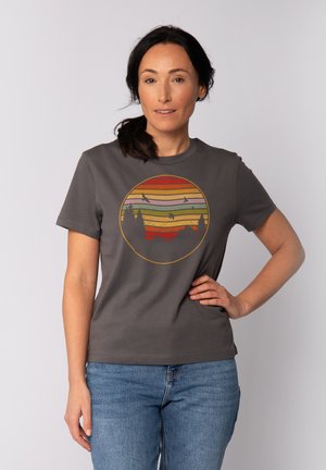 T-shirt en coton gris avec un graphique circulaire aux couleurs de coucher de soleil rayées horizontalement, silhouette d'arbres et d'oiseaux. Manches courtes.