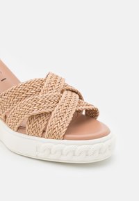 Sandale à enfiler beige avec bride tressée, semelle intérieure rembourrée et épaisse semelle extérieure blanche texturée.