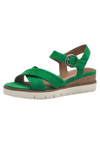 Sandali wedge verde in suede con cinghie incrociate, cinturino alla caviglia regolabile e suola in gomma bianca spessa. Piattaforma con effetto legno testurizzato.