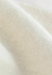Biała tkanina z filcu o miękkiej, włóknistej teksturze, lekko puszystym wyglądzie i gładkiej powierzchni, prezentująca monochromatyczny i neutralny design.
