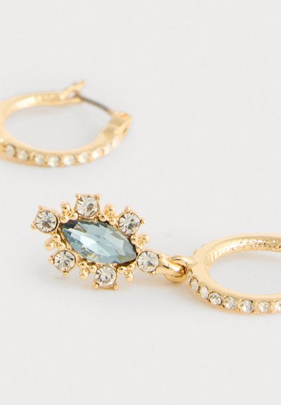 Gold hoop earrings with one featuring a central marquise blue gem surrounded by smaller clear crystals.