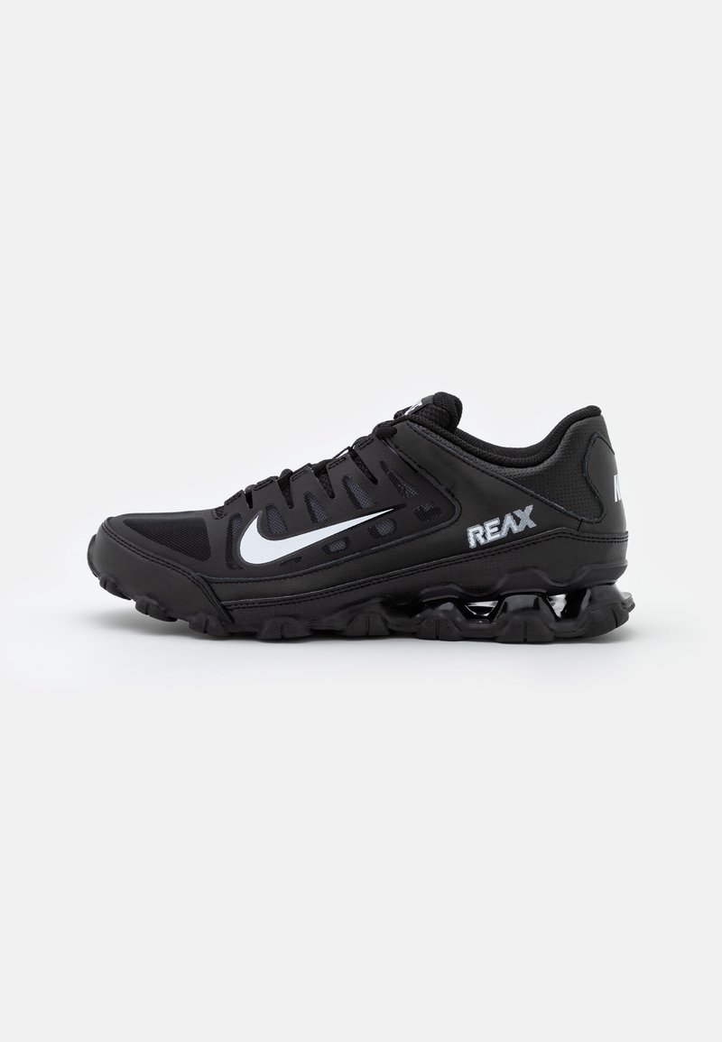 Baskets de sport noires avec logo blanc en forme de virgule, texte « REAX » sur le côté, semelle amortissante et design à lacets sur fond clair uni.