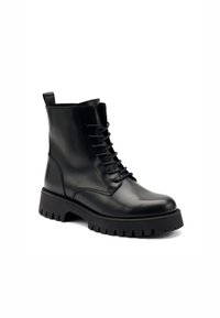 Botas de cuero negro hasta el tobillo, con punta redonda, cierre de cordones en el frente y suela de goma gruesa y resistente. Presenta una pestaña en la parte trasera.