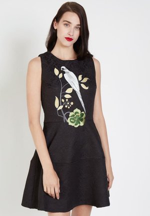 Vestido negro sin mangas con bordados de flores y pájaros en blanco, verde y amarillo, con un diseño texturizado y falda acampanada.