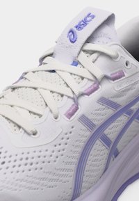 Λευκό και λεβαντίνι παπούτσι τρεξίματος ASICS GEL-CUMULUS με κορδόνια, πλεκτό πάνω μέρος και λογότυπο της μάρκας στη γλώσσα και στη πλευρά.