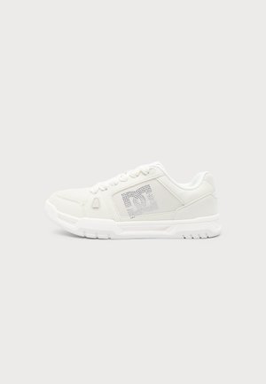 Λευκό χαμηλό sneaker με κλείσιμο με κορδόνια, υφασμένο πλαϊνό πάνελ με διάτρητο λογότυπο DC και παχιά καουτσούκ σόλα.