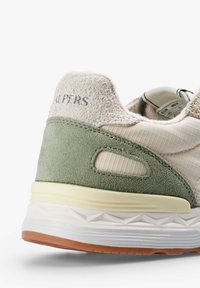 Tacón de zapatilla con paneles de ante beige y verde, parte superior de tela texturizada, suela blanca acolchada y etiqueta de tamaño parcial en el interior.