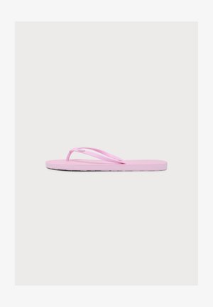 Une sandale tongs rose clair unique avec des fines lanières et une semelle plate sur un fond gris clair uni.