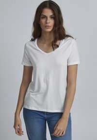 T-shirt bianco a maniche corte con scollatura a V, realizzato in cotone morbido, caratterizzato da una vestibilità rilassata e una texture liscia. Stile minimalista.
