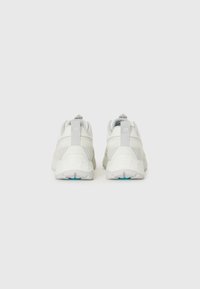 Weiße Sportschuhe mit einer strukturierten Oberseite, kontrastierenden grauen Akzenten und einer gepolsterten Sohle, die ein blaues Detail an der Außensohle aufweist.