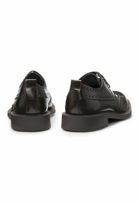 Scarpe in pelle marrone scuro con finitura liscia, dettagli brogue, modello stringato e suola in gomma contrastante con texture rigata.