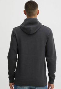 Mørkegrå hoodie med en tekstureret overflade, der har hætte, lange ærmer og ribkantede manchetter. Bagfra viser den en glat silhuet.