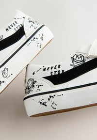 Białe sneakersy z czarnymi akcentami. Skórka teksturowana, graficzne nadruki i detale w stylu rozprysku. Rzep do zapięcia, gumowa podeszwa.