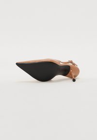 Chaussure à talon aiguille à bout pointu en matière synthétique marron clair; dotée d'une délicate bride de cheville et d'une semelle noire texturée.