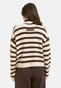 Cream and brown striped knit sweater with a high collar and logo patch at the back. Soft texture, cropped design, and dropped shoulder seams.