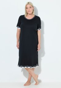 Vestito da notte nero in morbido tessuto, alla ginocchio, con maniche corte e bordo bianco e dettagli in pizzo all'orlo e alle maniche. Bordo ondulato.