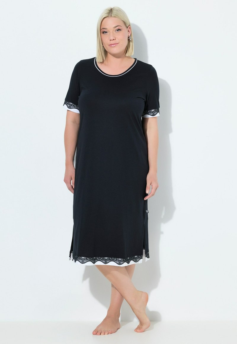 Vestito da notte nero in morbido tessuto, alla ginocchio, con maniche corte e bordo bianco e dettagli in pizzo all'orlo e alle maniche. Bordo ondulato.