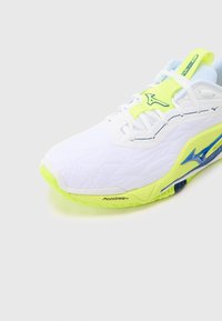 Λευκό και νέον κίτρινο αθλητικό παπούτσι Mizuno με άνω μέρος από δίχτυ, μπλε λογότυπο και ορατό κείμενο "Mizuno Energy" στην πλευρά της σόλας.