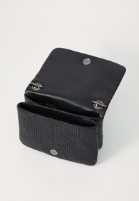 Borsa in pelle nera con motivo geometrico strutturato, dotata di chiusura a bottone automatico e patta liscia a contrasto. Visibili più scomparti.