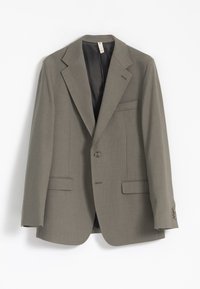 Blazer gris claro hecho de una tela texturizada, con solapas de muesca, dos bolsillos frontales y cierre de un botón. El forro interior es oscuro.