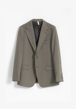 Blazer gris claro hecho de una tela texturizada, con solapas de muesca, dos bolsillos frontales y cierre de un botón. El forro interior es oscuro.