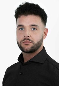 Zwarte overhemdd met een gestructureerde kraag en textuurstof. Strak ontwerp zonder zichtbare patronen. Onderwerp heeft kort, donker haar en een baard.