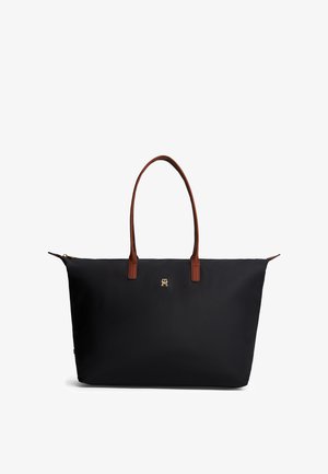 Sort mulepose med brune læderhåndtag og et lille gyldent logo foran, på hvid baggrund.