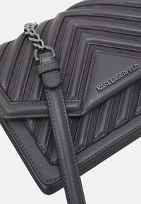 Borsa a tracolla grigia con trapuntatura, realizzata con una combinazione di pelle liscia e testurizzata, dotata di una tracolla in catena metallica e di una placca con il logo "KARL LAGERFELD".