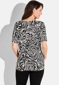 T-shirt met korte mouwen, voorzien van een zwart en crème wervelpatern, gemaakt van een zachte stof met een ronde halslijn en een gebogen zoomdesign.