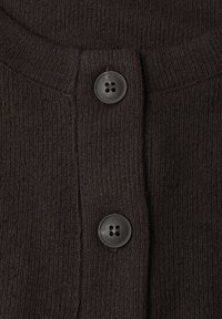 Close-up af mørkebrunt strikket stof med to store blanke sorte firehuls knapper, der er justeret lodret.