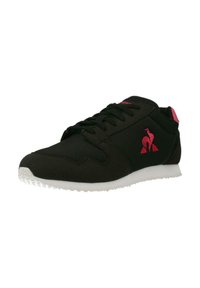 Scarpa sportiva nera con tessuto in rete, accento rosa e suola in gomma bianca. Presenta un design tradizionale con lacci e un logo sul lato.
