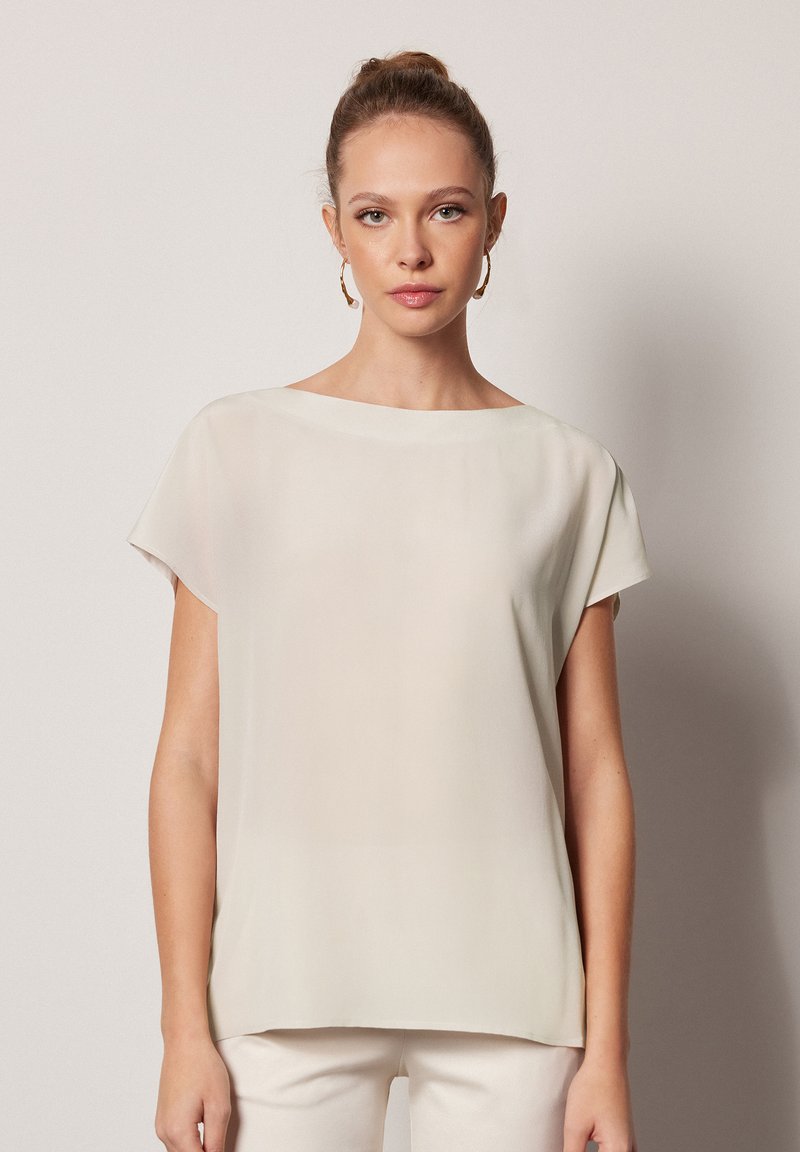 Ljusbeige kortärmad topp med båtutskärning, tillverkad av ett mjukt, något genomskinligt tyg, med en avslappnad passform och enkelt design.